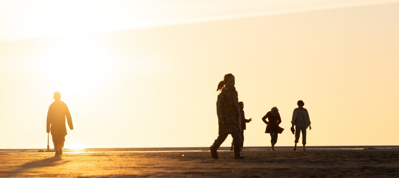 Familie läuft über den Strand bei Sonnenuntergang