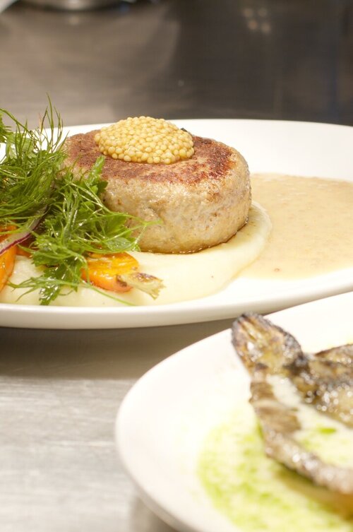 Detailansicht von zwei Gerichten, einmal Fisch, einmal Fleisch